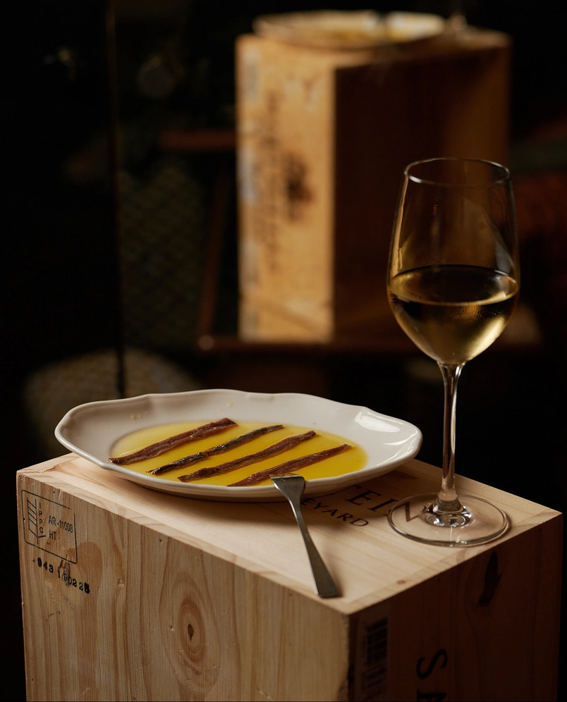 Degustación gourmet de anchoas y vino blanco en el elegante entorno del hotel Regina Experimental de Biarritz.