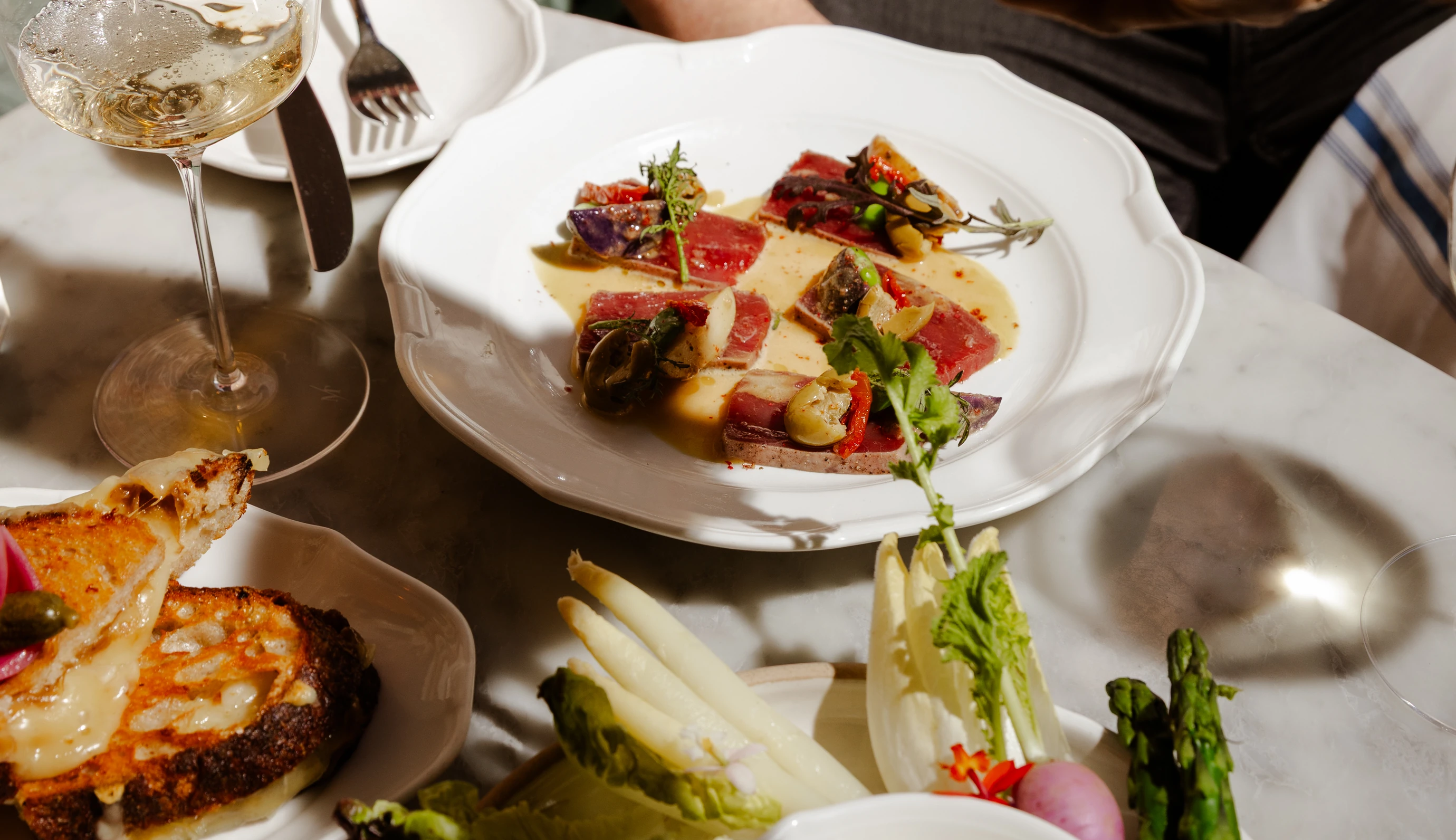 Exquisite culinary presentation featuring tuna tataki and gourmet appetizers on a marble table at an Experimental Group location.