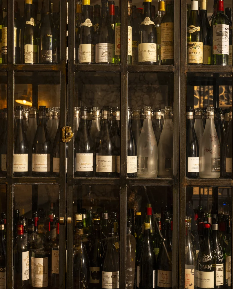 Close-up of a glass wine cellar cabinet filled with premium bottles, located in an Experimental Group bar in London.