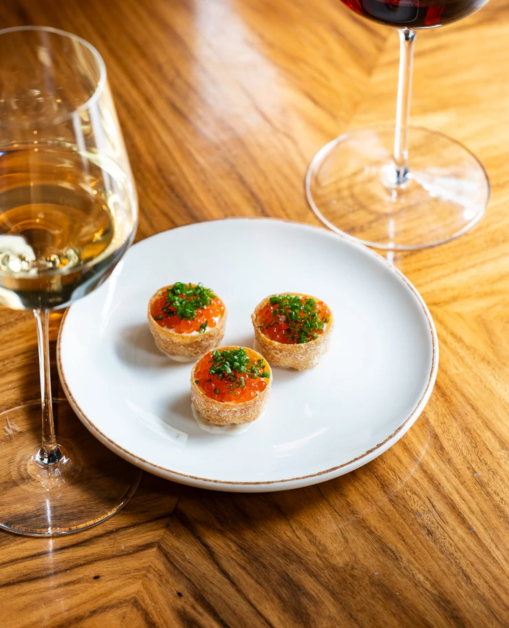 Refined canapés topped with fish roe and chives, a gourmet creation by Experimental Group.