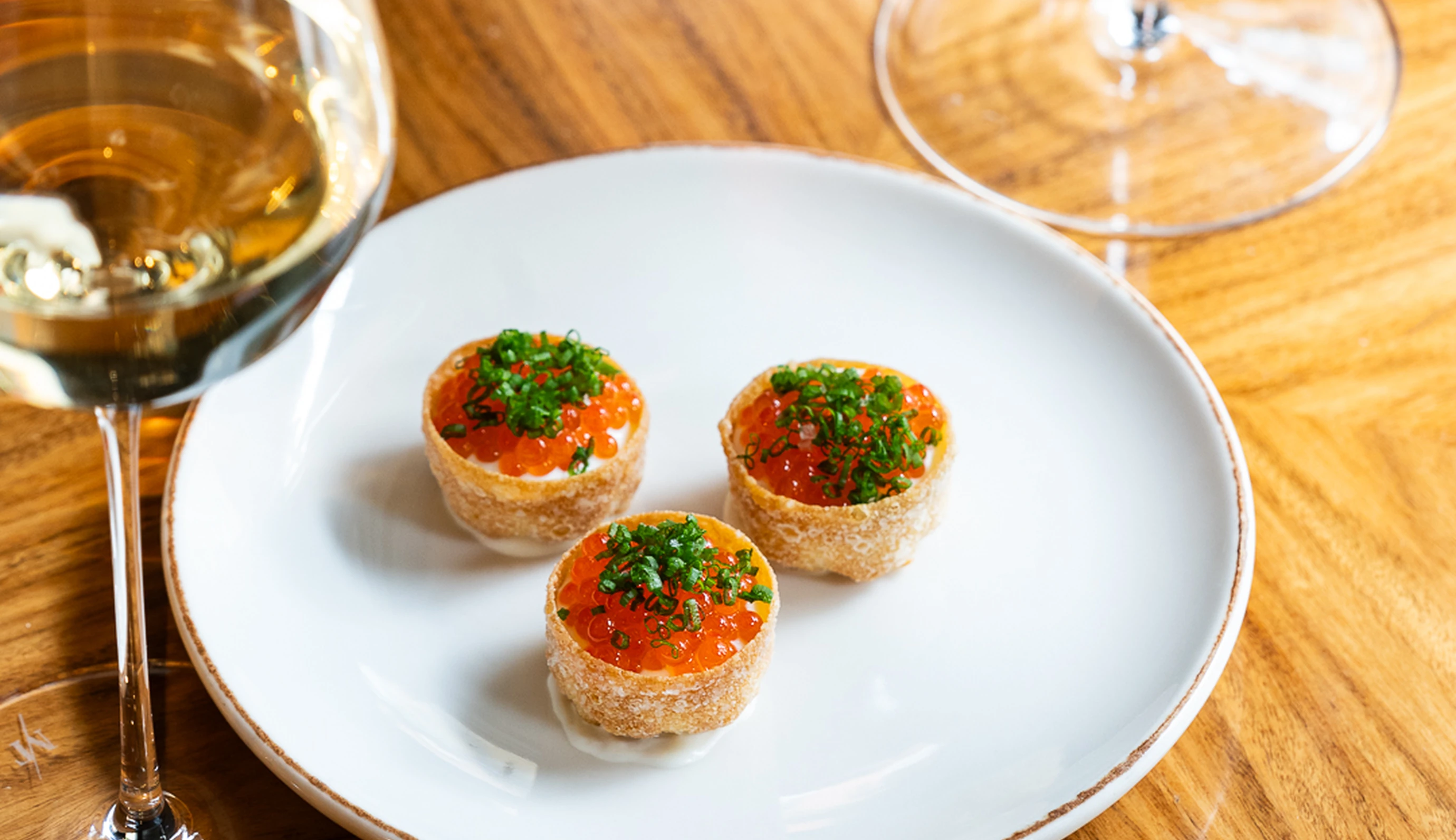 Refined canapés topped with fish roe and chives, a gourmet creation by Experimental Group.