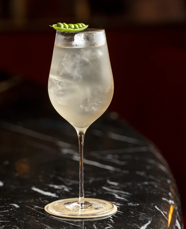 Cocktail sofisticato guarnito con piselli, esperienza nella mixologia di Experimental Group.