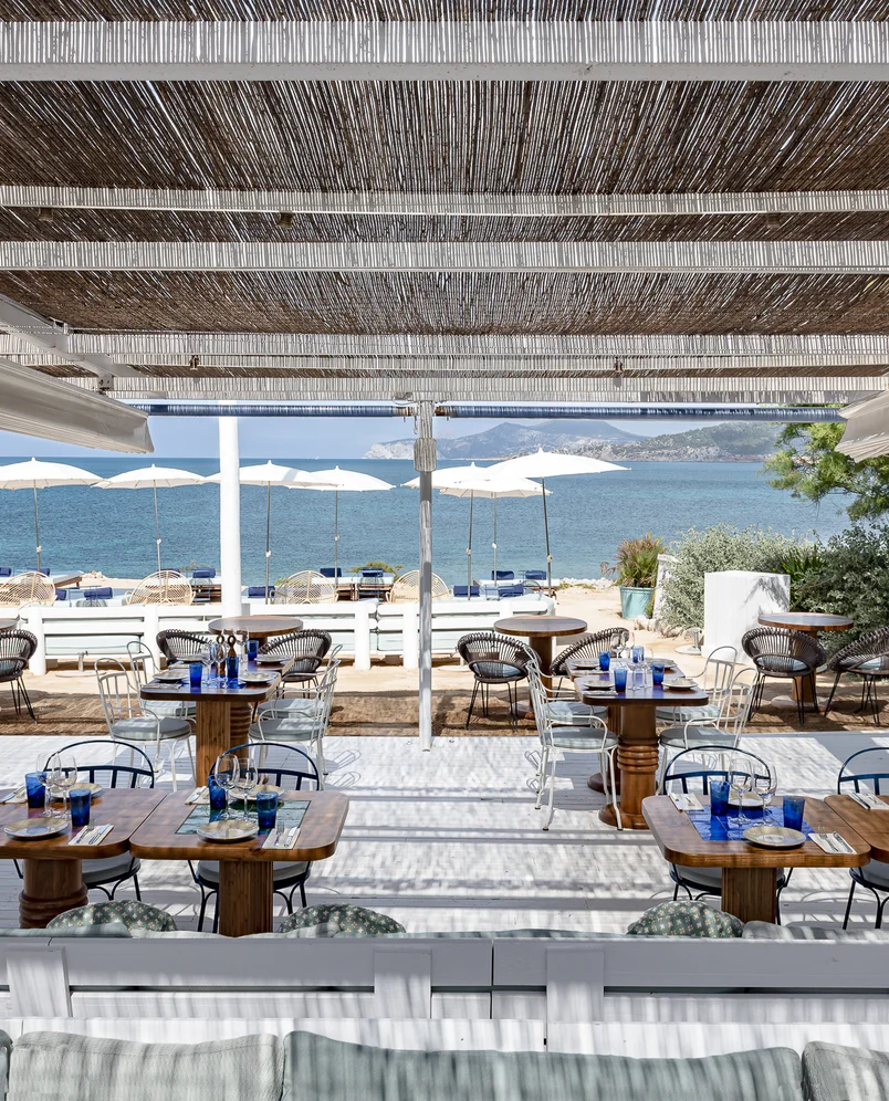 Terrazza del ristorante Experimental Group sul mare con vista panoramica e ombrelloni bianchi.