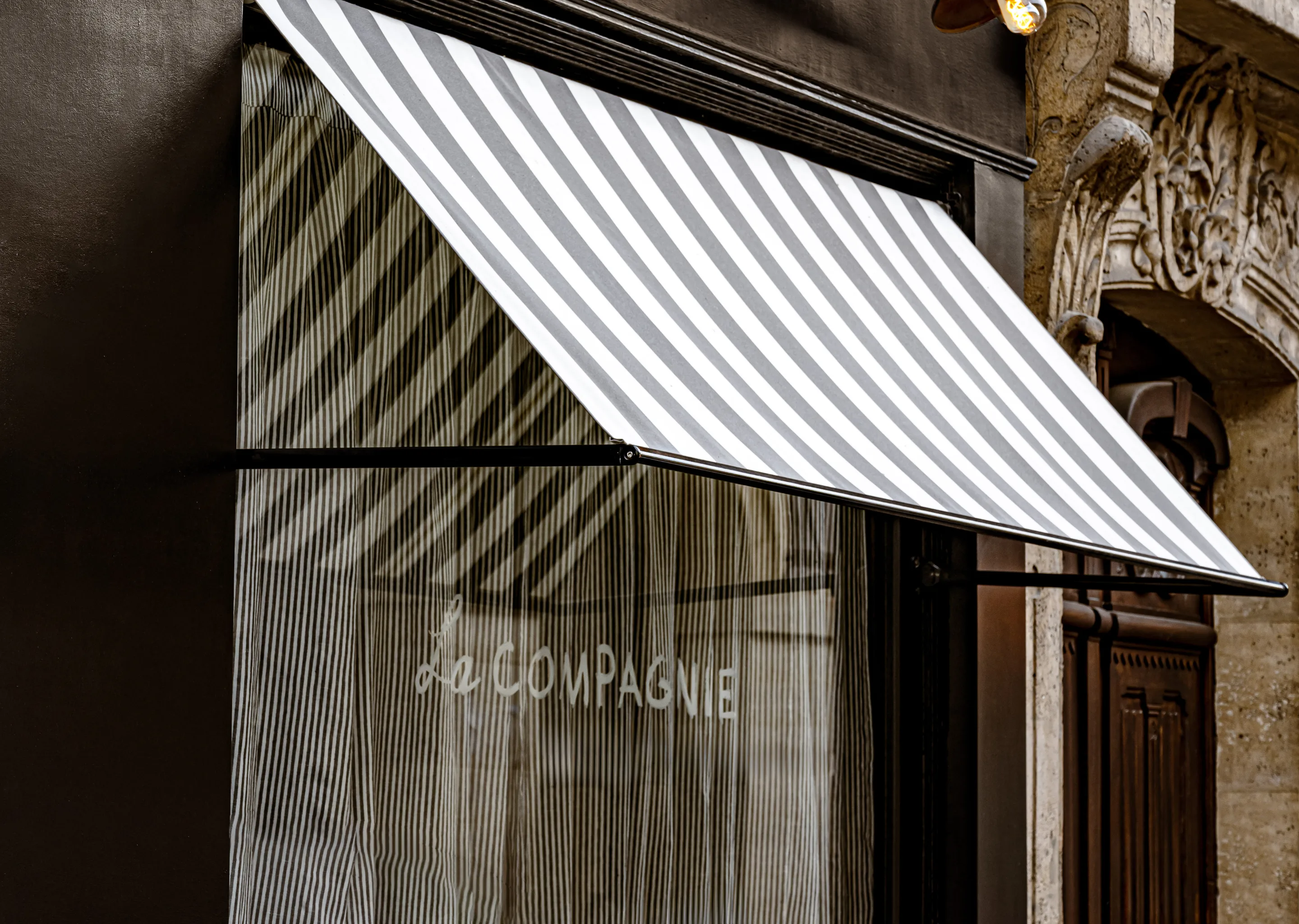 Facade and striped awning of La Compagnie, an Experimental Group property in Paris.