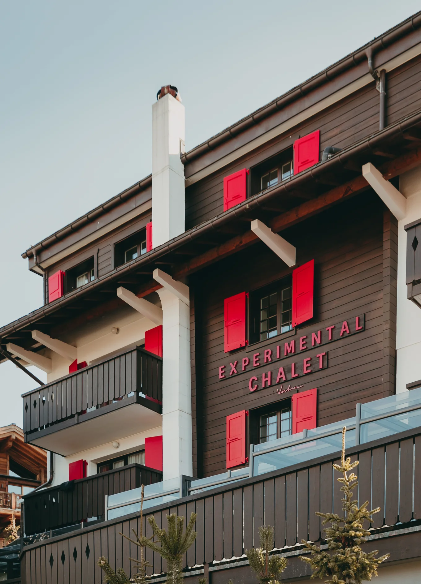 The exterior of the Experimental Chalet in Verbier, showcasing its signature red shutters and mountain style, Experimental Group.