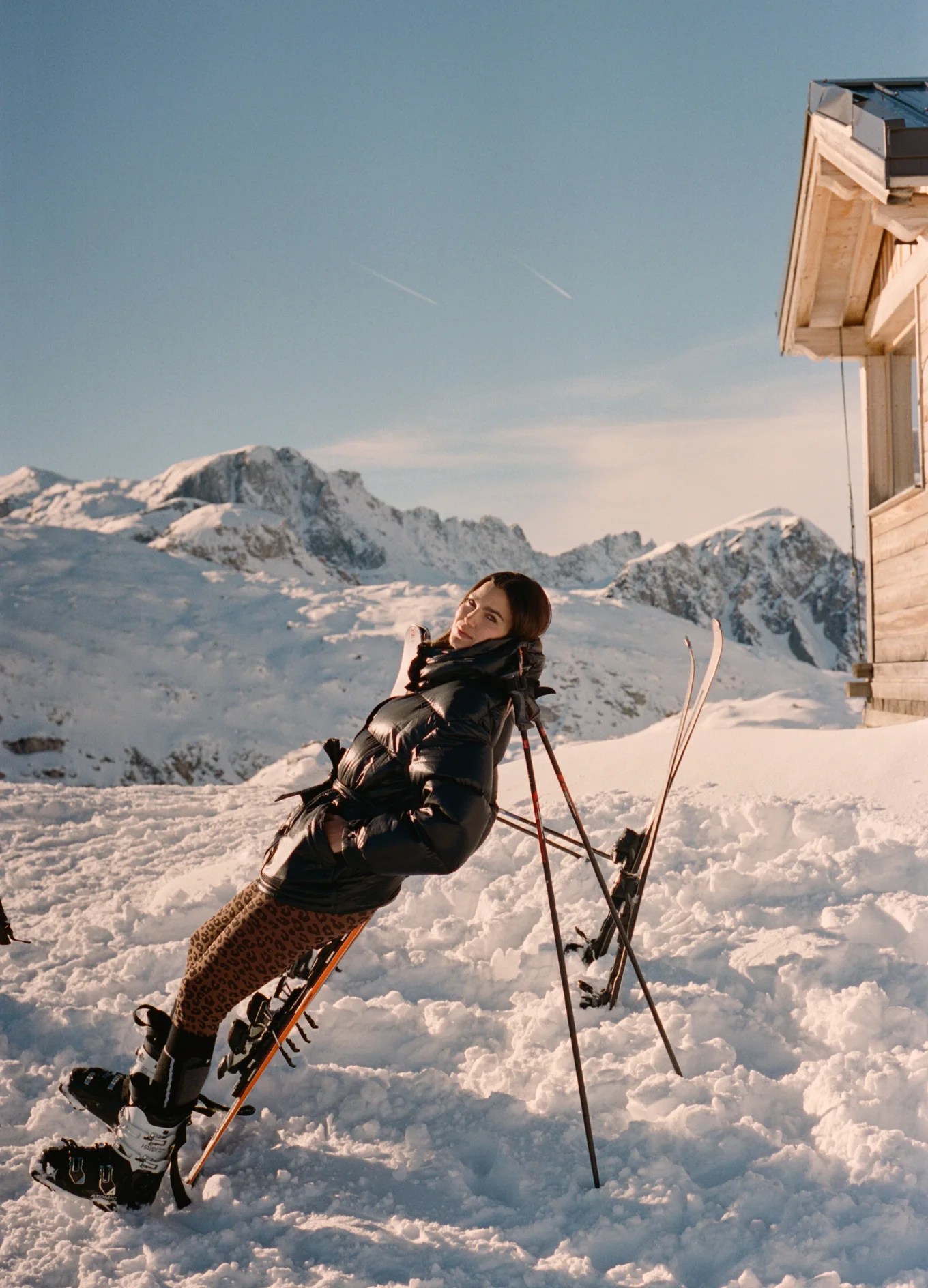 A woman posing with skis in a snowy alpine landscape at Experimental Chalet, Verbier, Experimental Group.