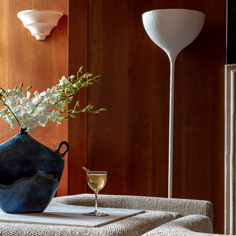 Elegant interior featuring a vase of white flowers and a cocktail placed on a cushion at Palazzo Experimental, Venice.