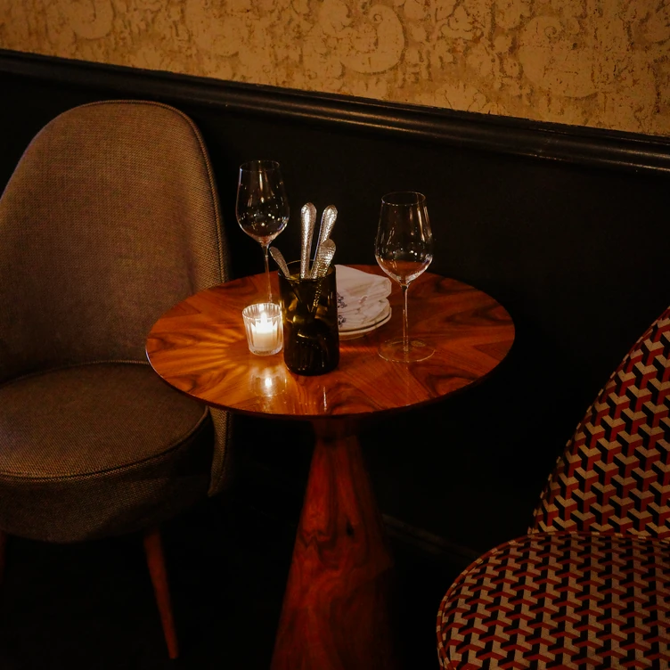 Close-up view of a marble fireplace decorated with candles, a clock, and a cocktail at La Compagnie des Vins Surnaturels, London