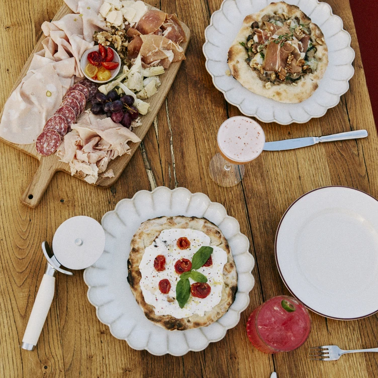 Tagliere di salumi e pizze su un tavolo di legno presso il Gruppo Sperimentale.