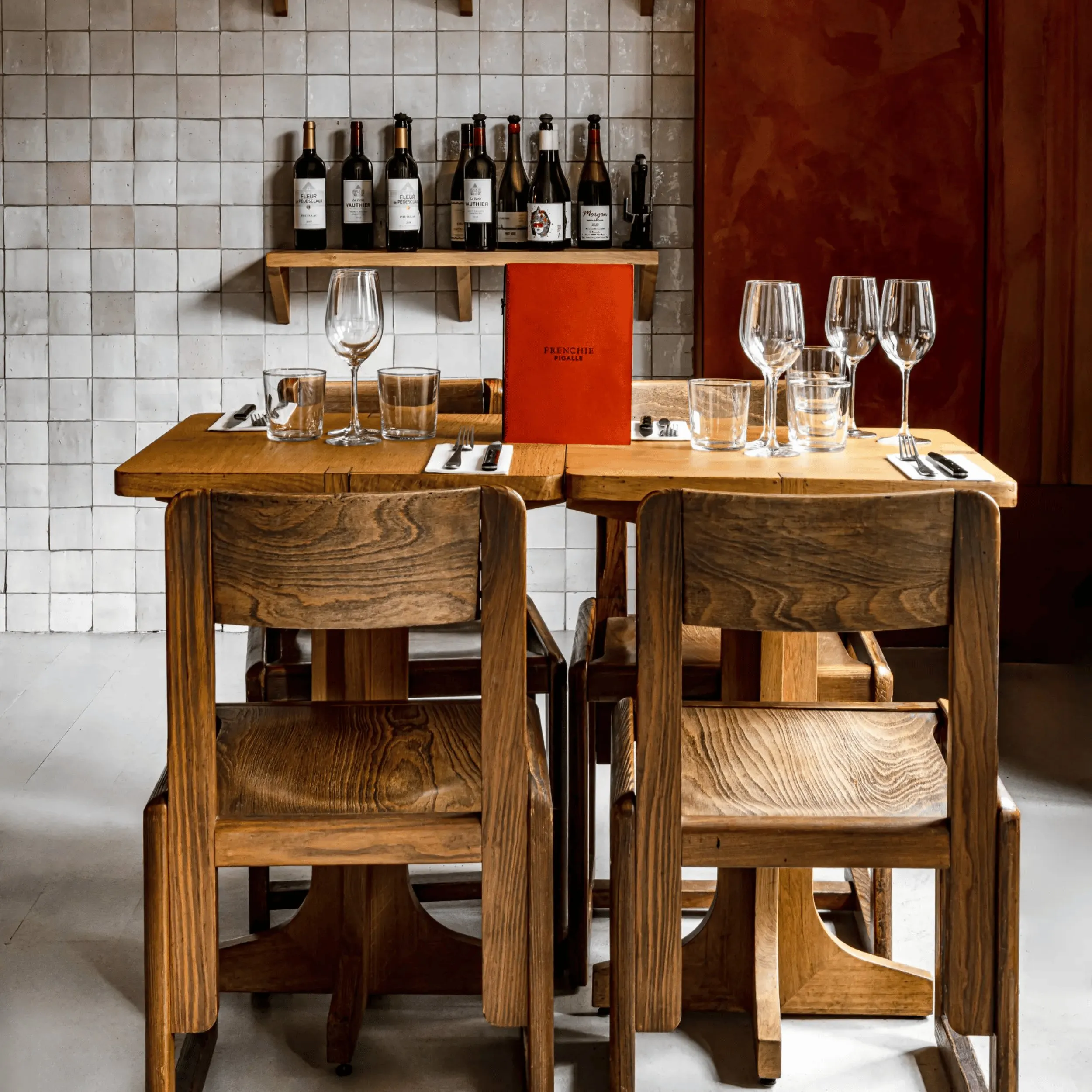 Set da tavola in legno per quattro persone con bicchieri da vino, posate e un menù all'arancia in un ristorante.