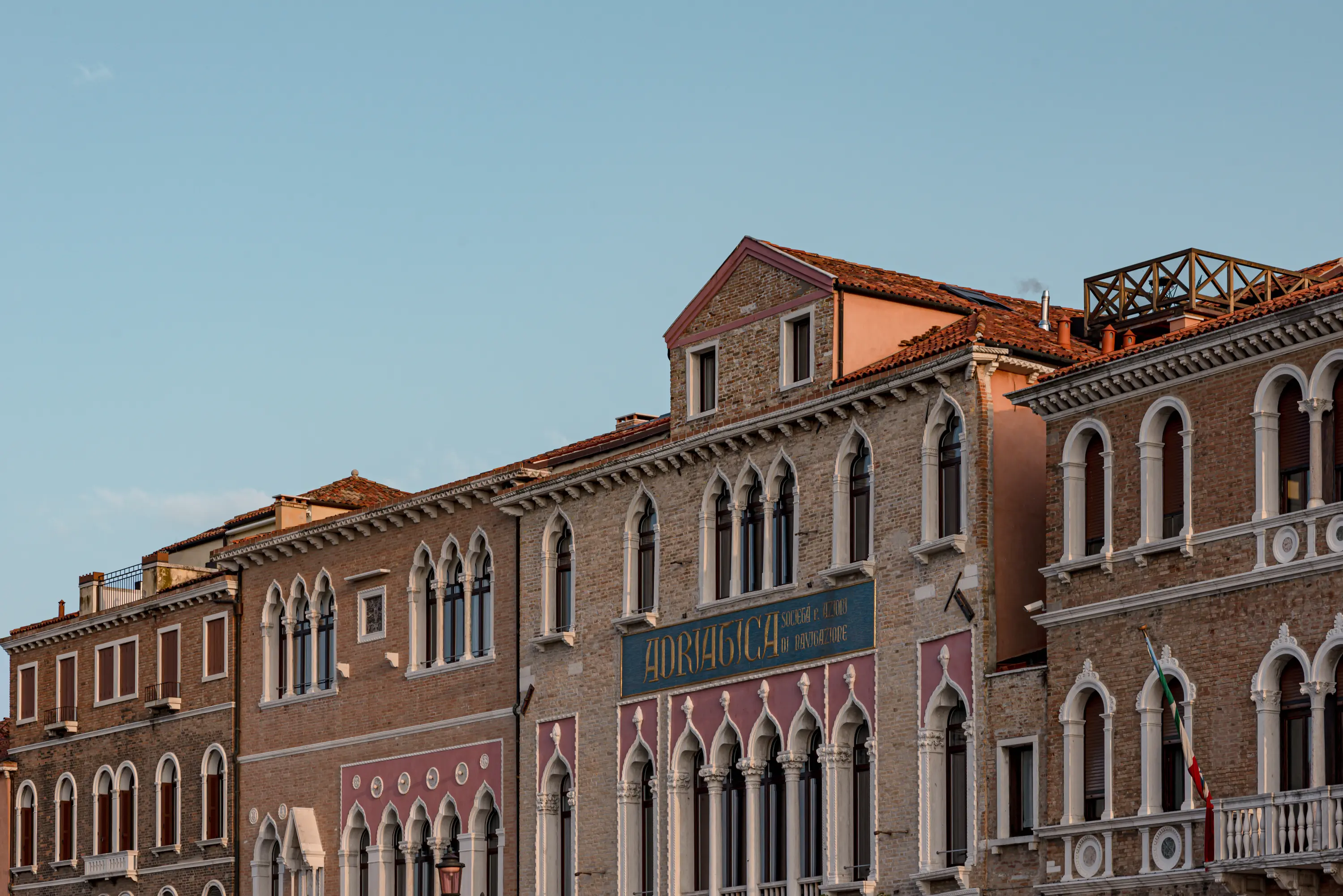 Fachada de edificios históricos de ladrillo con ventanas arqueadas bajo un cielo azul claro.
