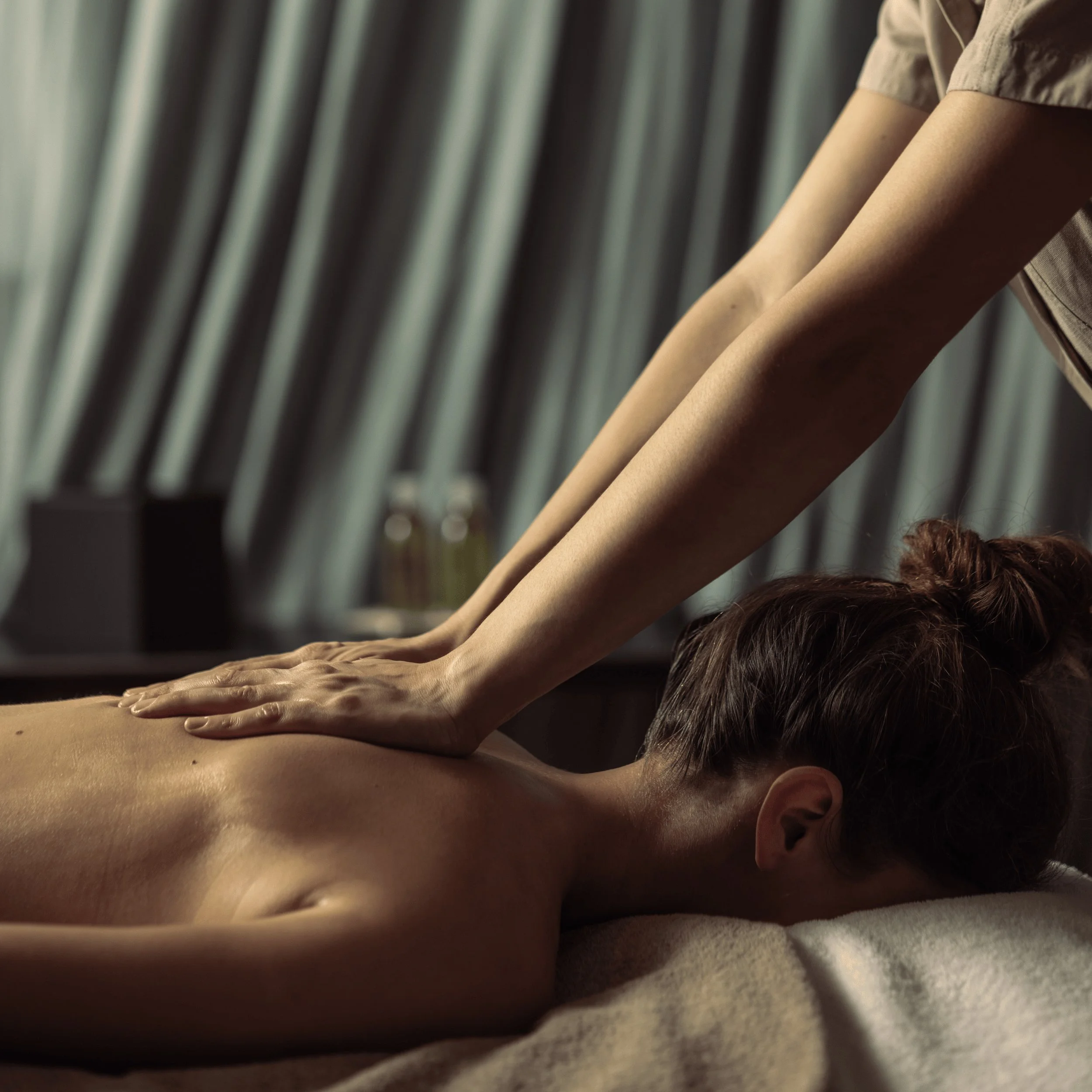 Persona che riceve un massaggio alla schiena con le mani del terapista che premono sulla parte superiore della schiena in un ambiente spa.