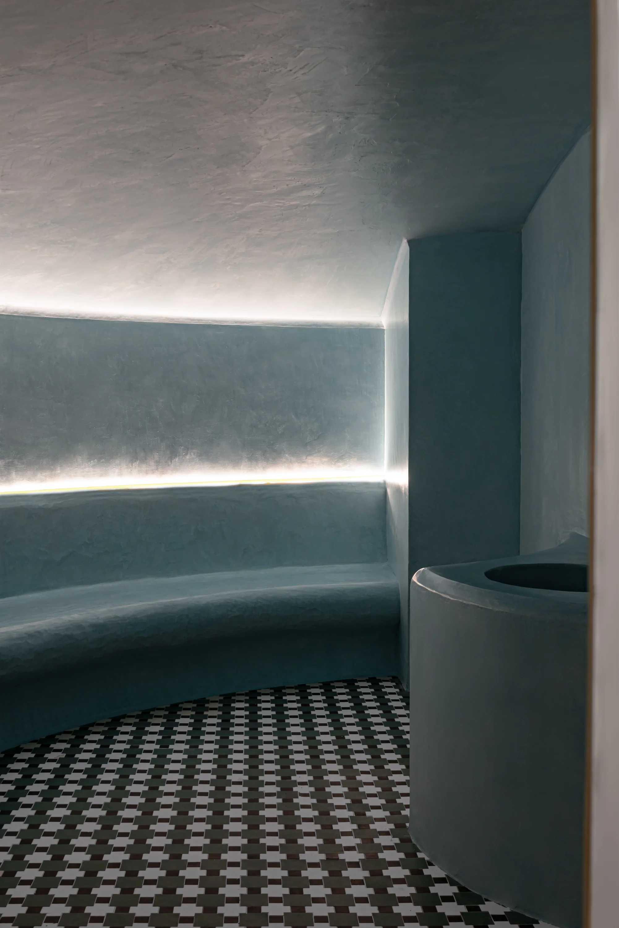 Curved blue seating area in a dimly lit room with patterned black and white tile floor.