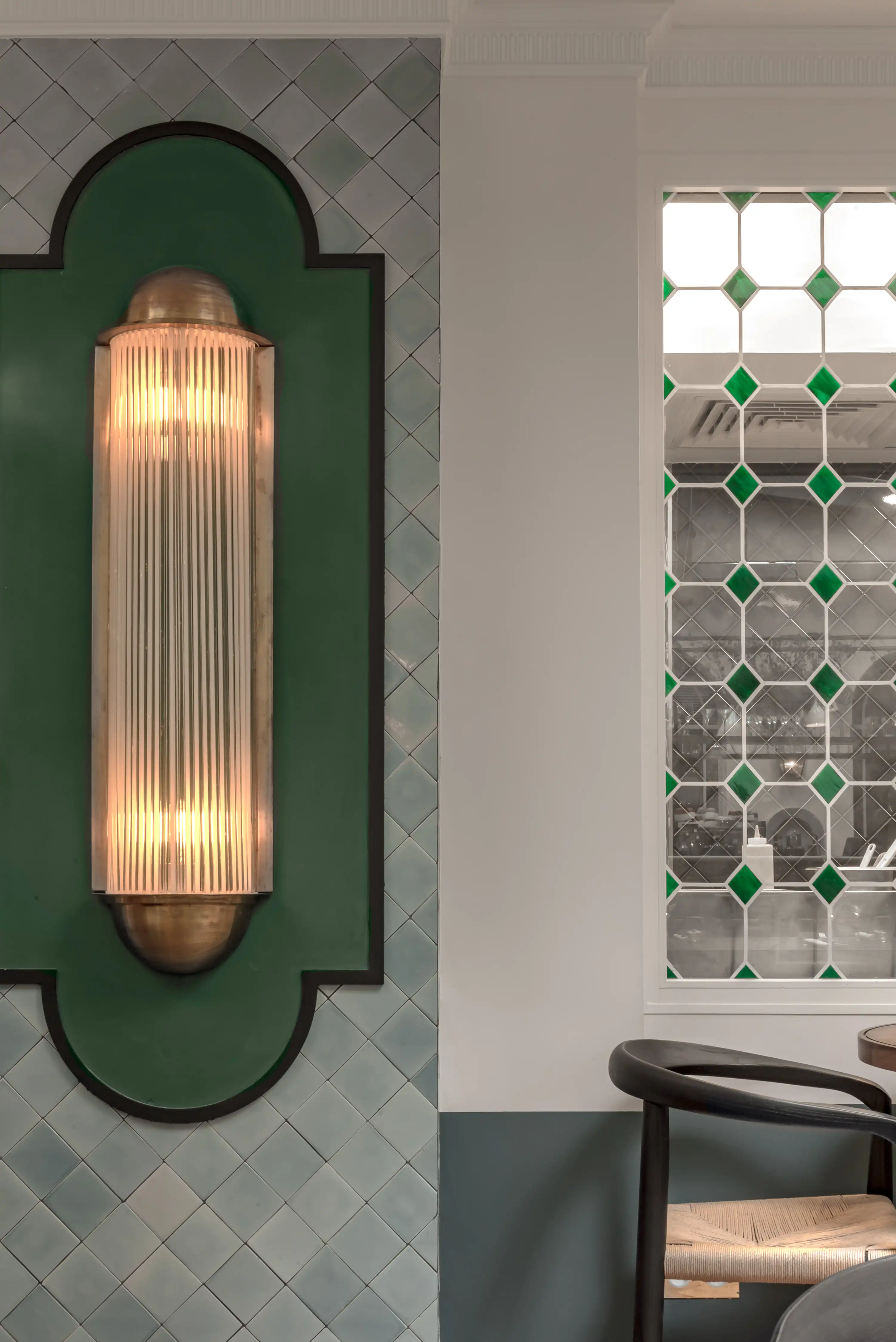 Luz de parede com vidro nervurado vertical montado em painel verde ao lado da janela com padrão de diamante verde.