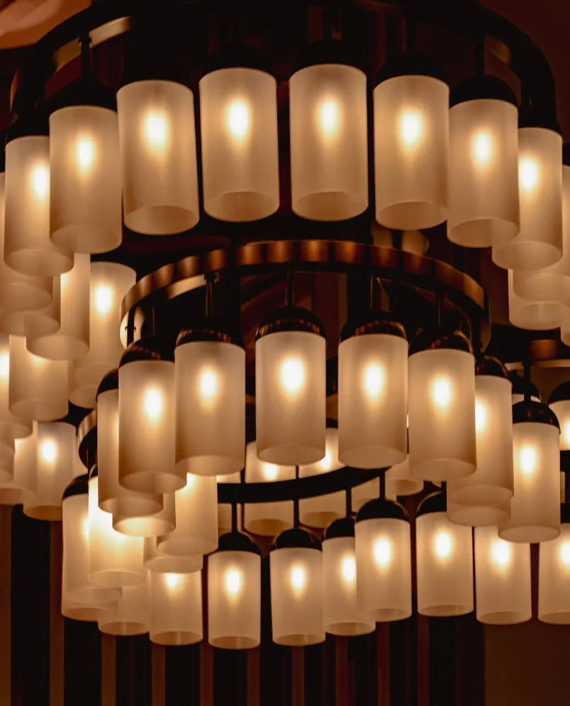Lampadario circolare moderno con più lampade cilindriche in vetro satinato che brillano calorosamente.