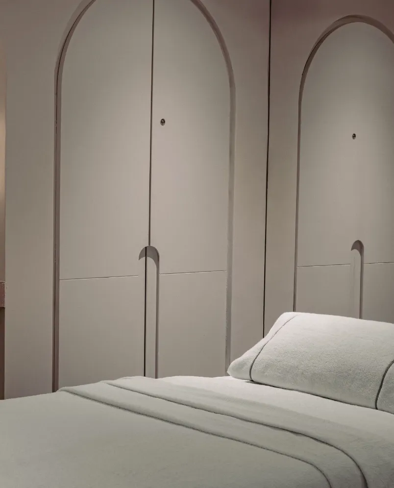 Camera da letto minimalista con un letto ben fatto e ante ad arco sullo sfondo.