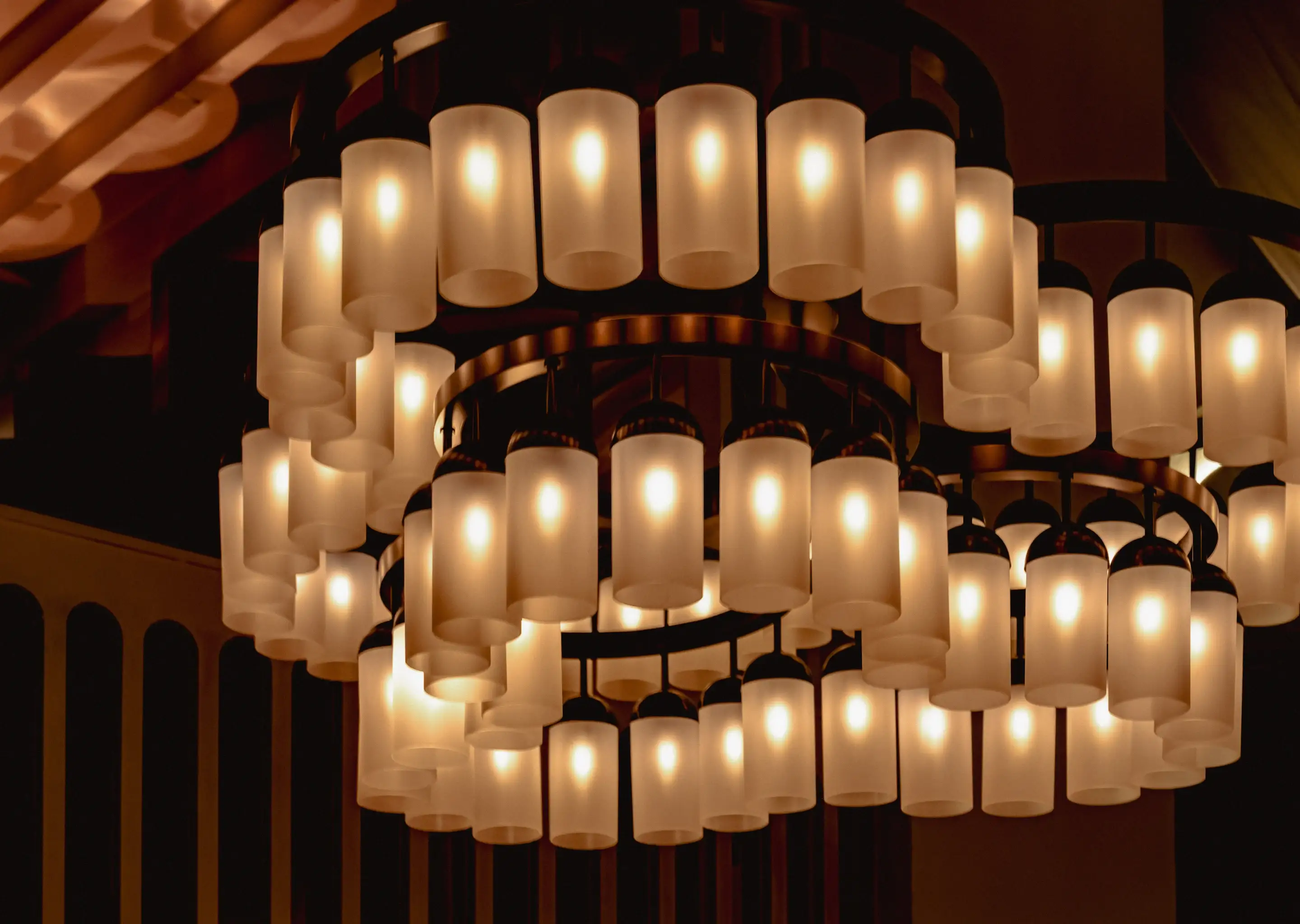 Lampadari circolari con più luci cilindriche in vetro satinato che brillano calorosamente all'interno.