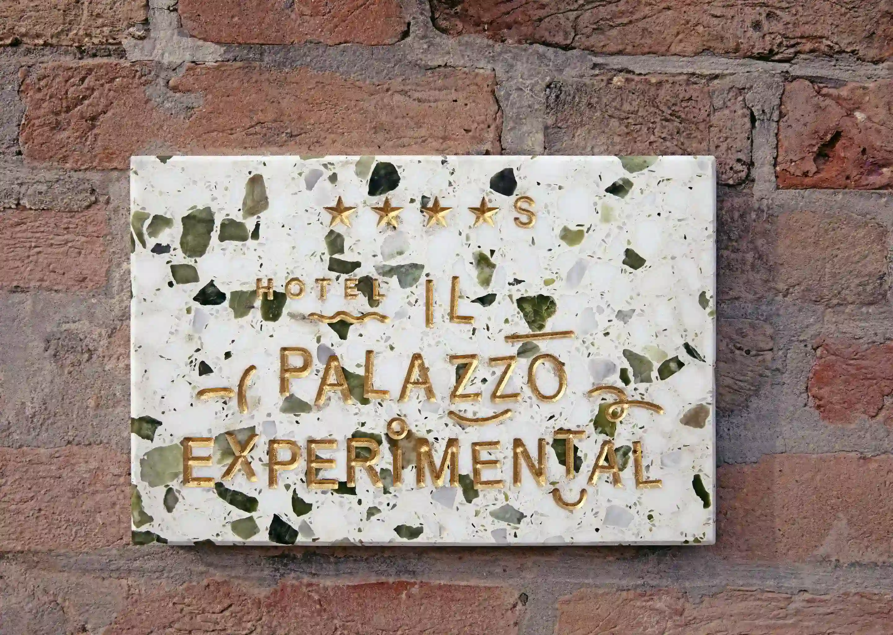 Placa experimental do Hotel Il Palazzo com quatro estrelas em uma placa de terraço em uma parede de tijolos.