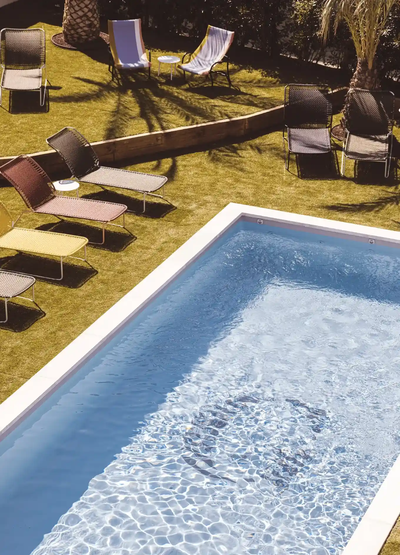Piscina all'aperto con disegno a teschio nella parte inferiore e sedie a sdraio colorate sull'erba nelle vicinanze.