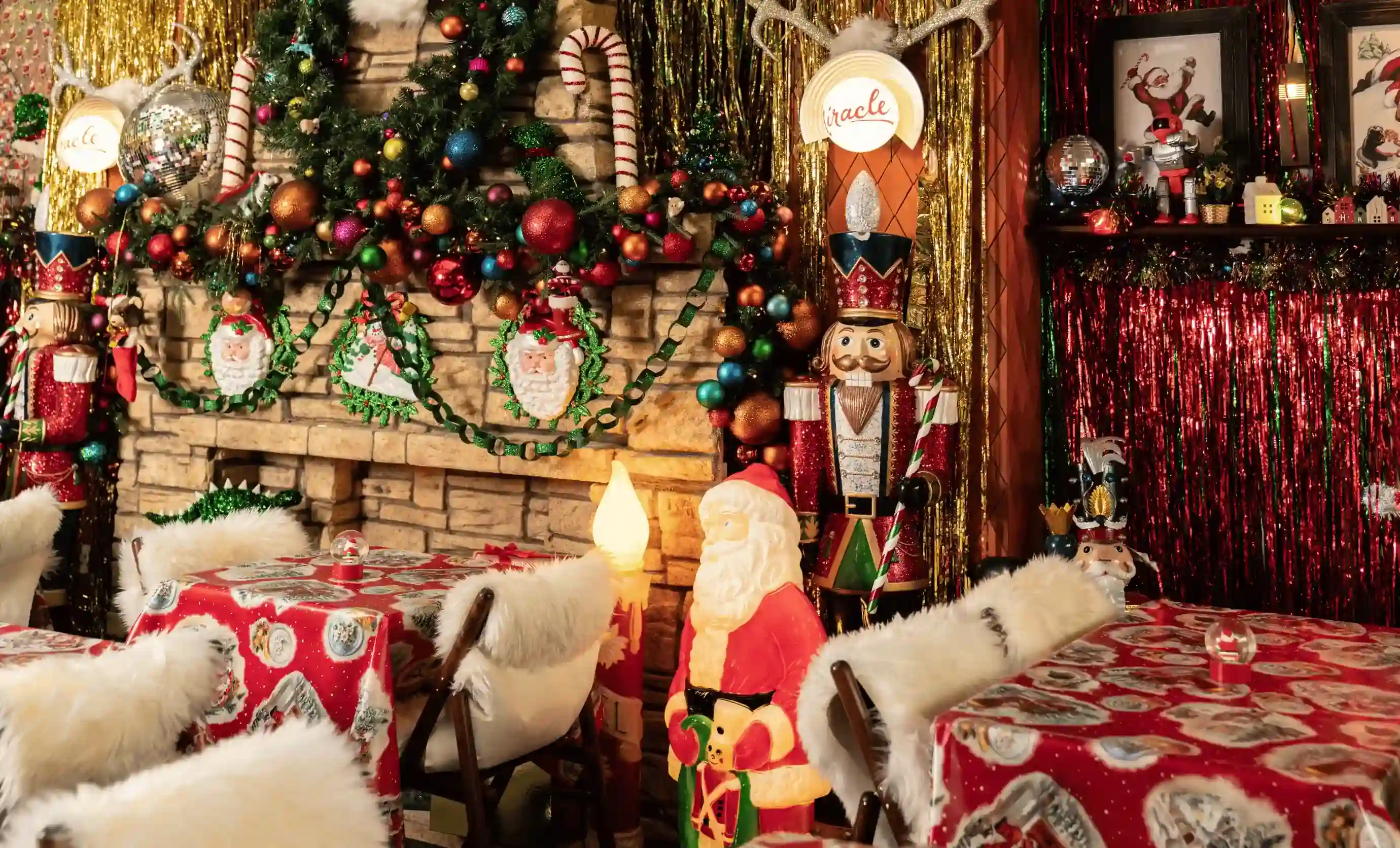 Quarto aconchegante com decoração de Natal: figura do Papai Noel, quebra-nozes, coroa de flores, enfeites e toalhas de mesa vermelhas.