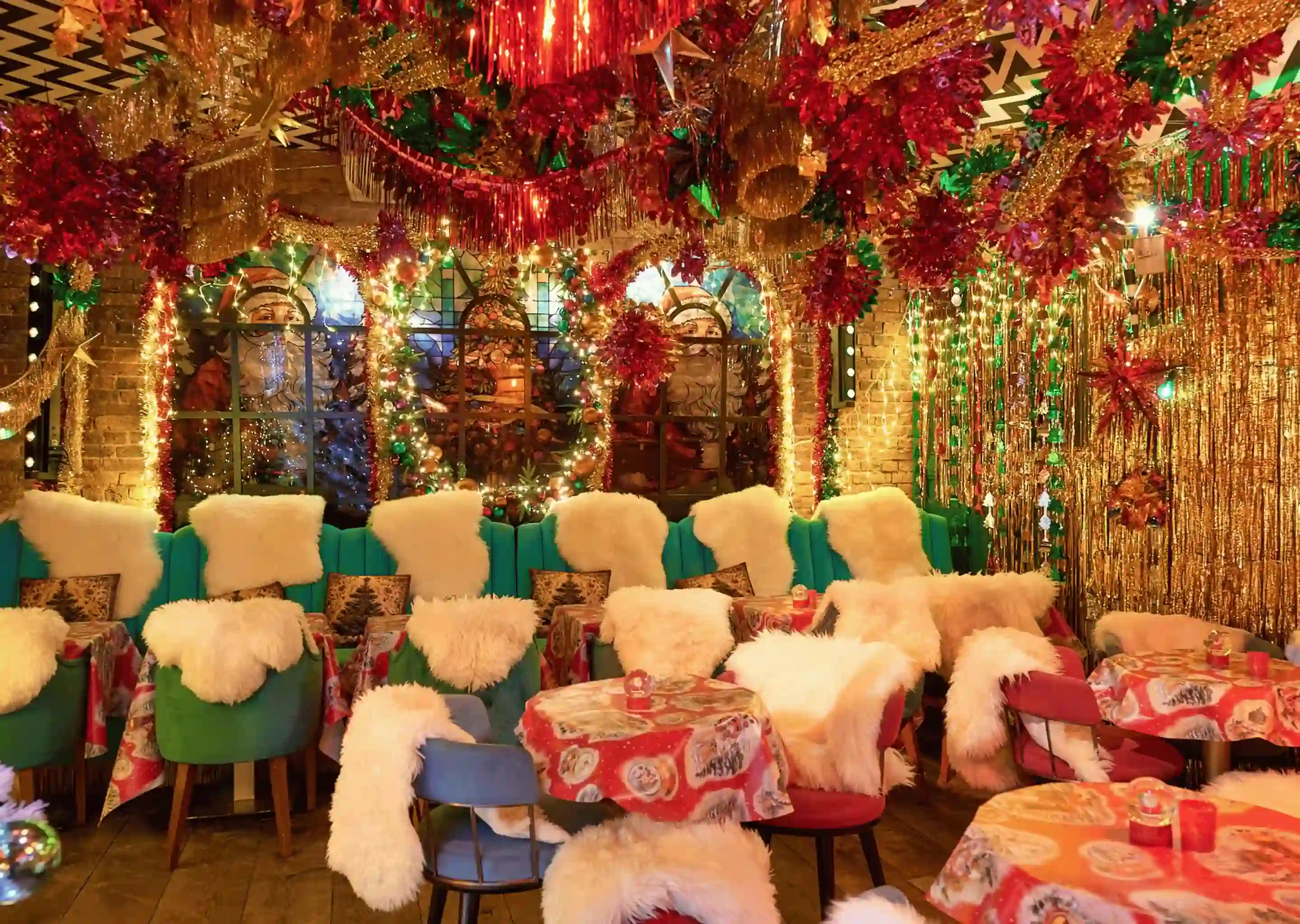 Sala festiva aconchegante com cadeiras cobertas de pele, guirlandas, luzes e toalhas de mesa com temas natalinos.