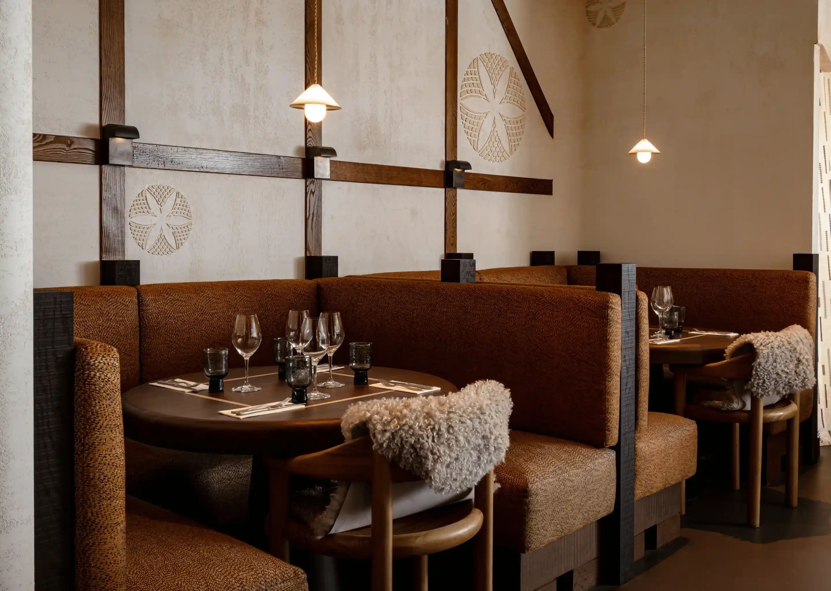 Estandes de restaurante aconchegantes com estofamento marrom, cadeiras de madeira e luminárias pendentes fracas em paredes texturizadas.