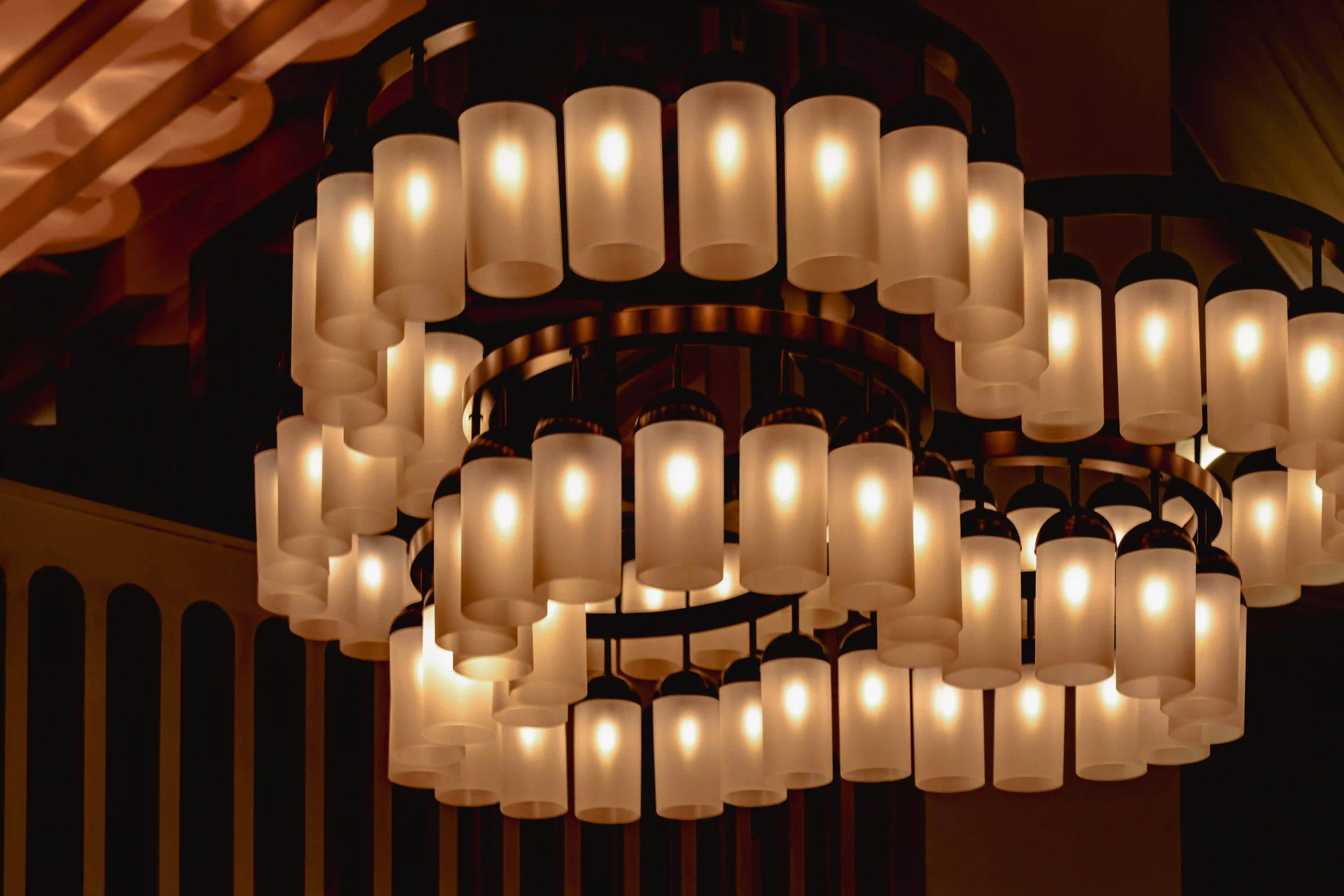 Moderna lámpara circular con múltiples lámparas cilíndricas de vidrio esmerilado iluminadas cálidamente.