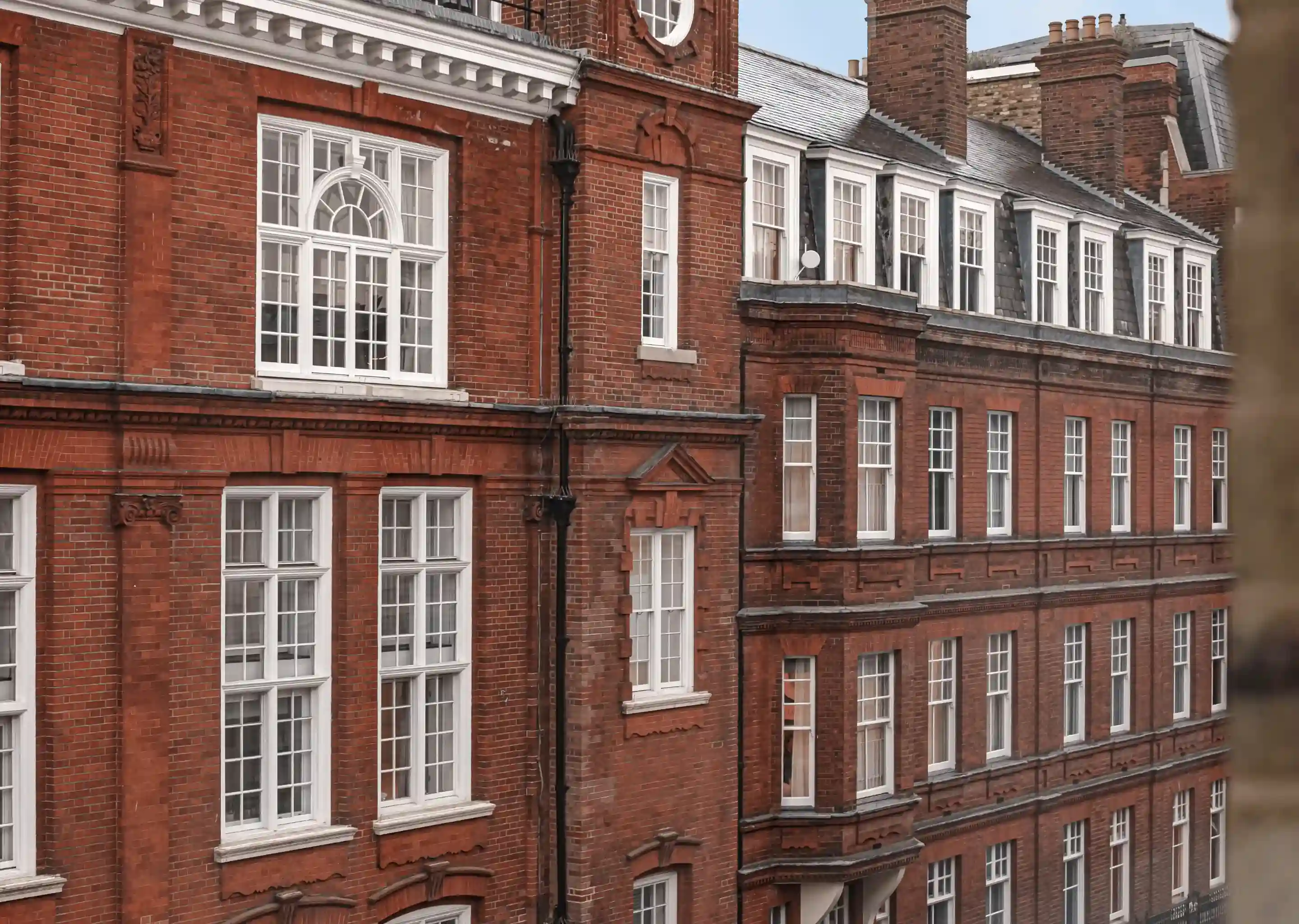 Red brick building facade with multiple white-framed windows and decorative architectural details.