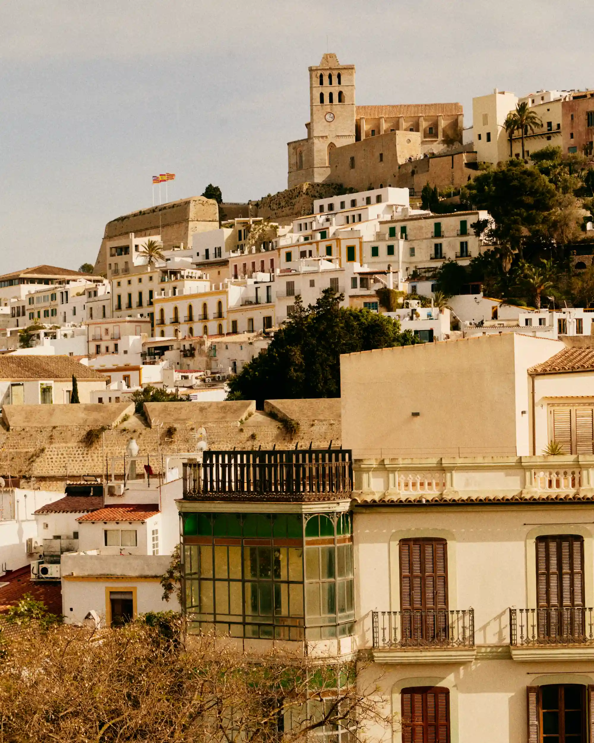 Hilltop town with white buildings and a clock tower under a clear sky.