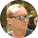 Man wearing sunglasses and looking to the side outdoors.