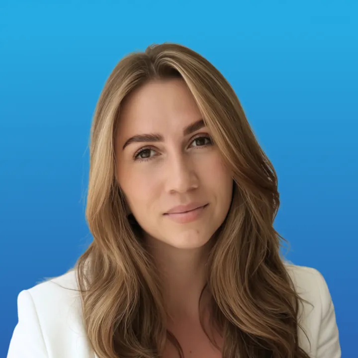 Portrait of a woman with long light brown hair wearing a white blazer, against a blue gradient background.
