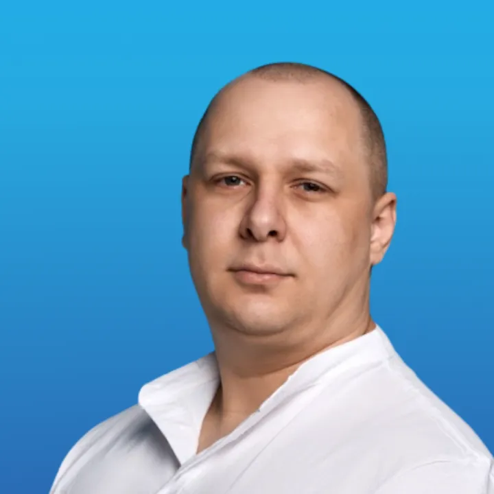 Portrait of a bald man wearing a white shirt against a blue background.
