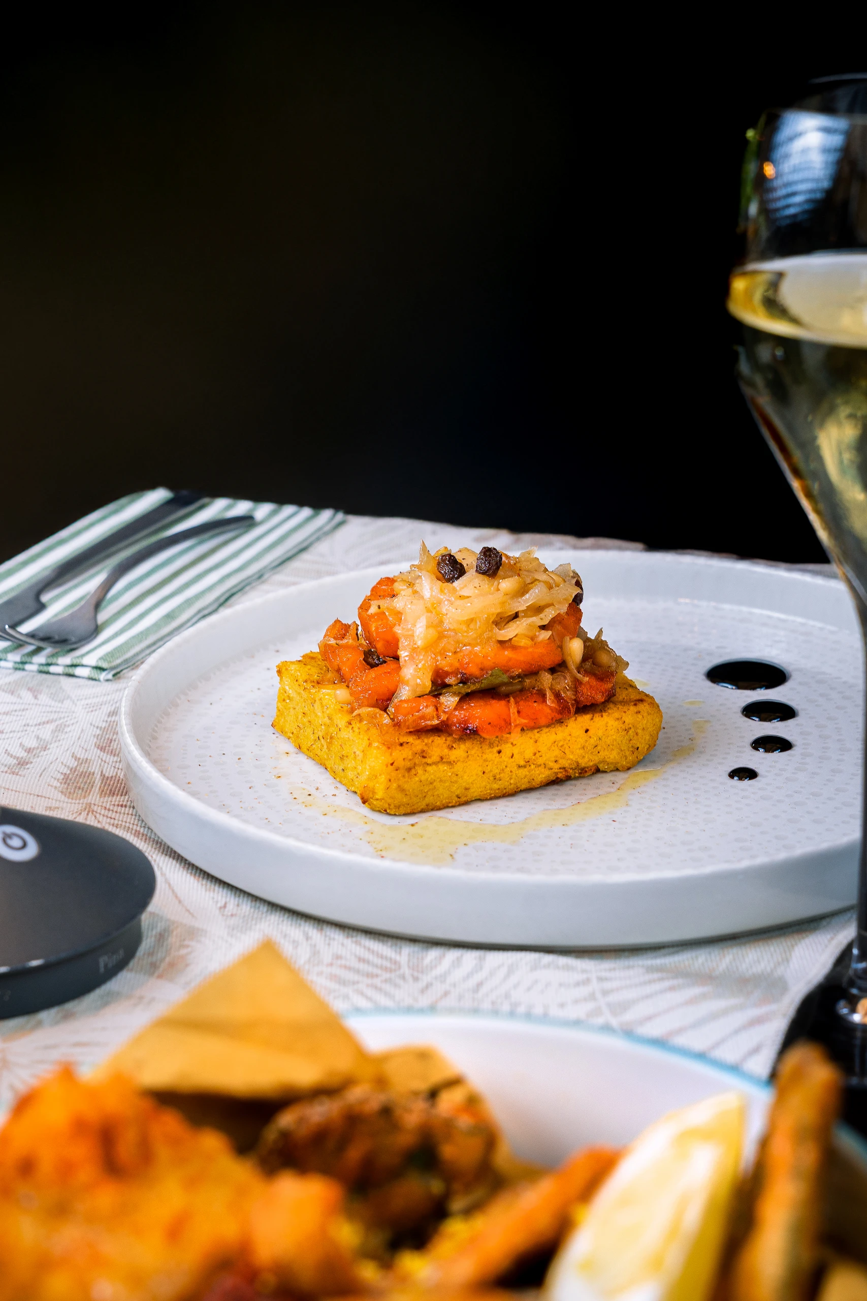 Le Bande Ristorante Cavriana, Shooting Studio Looma. Piatto bianco con base di polenta gialla sormontata da carote arrostite e cipolle caramellate con gocce di salsa balsamica.