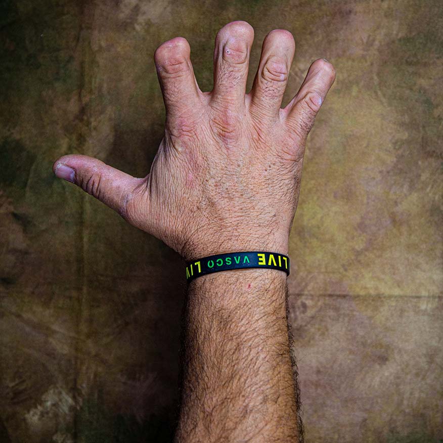 I segni del mestiere, Campagna sociale. Mano maschile con dita deformate e polso con braccialetto nero con scritta colorata.