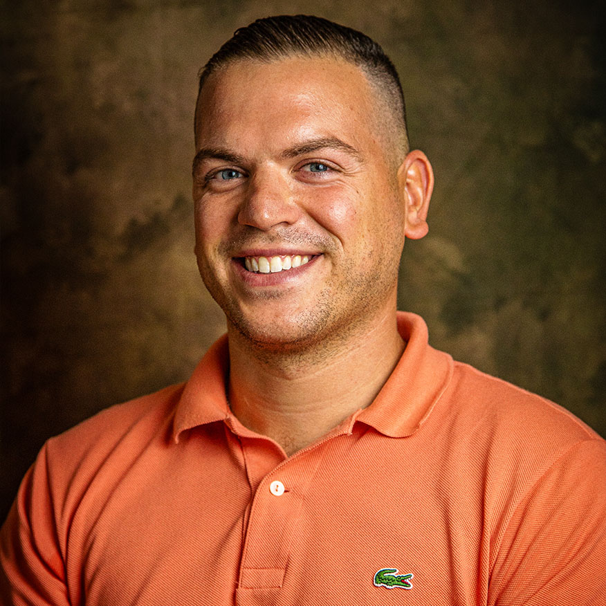 I segni del mestiere, Campagna sociale. Uomo sorridente con capelli corti e occhi azzurri che indossa una polo arancione con logo di coccodrillo.