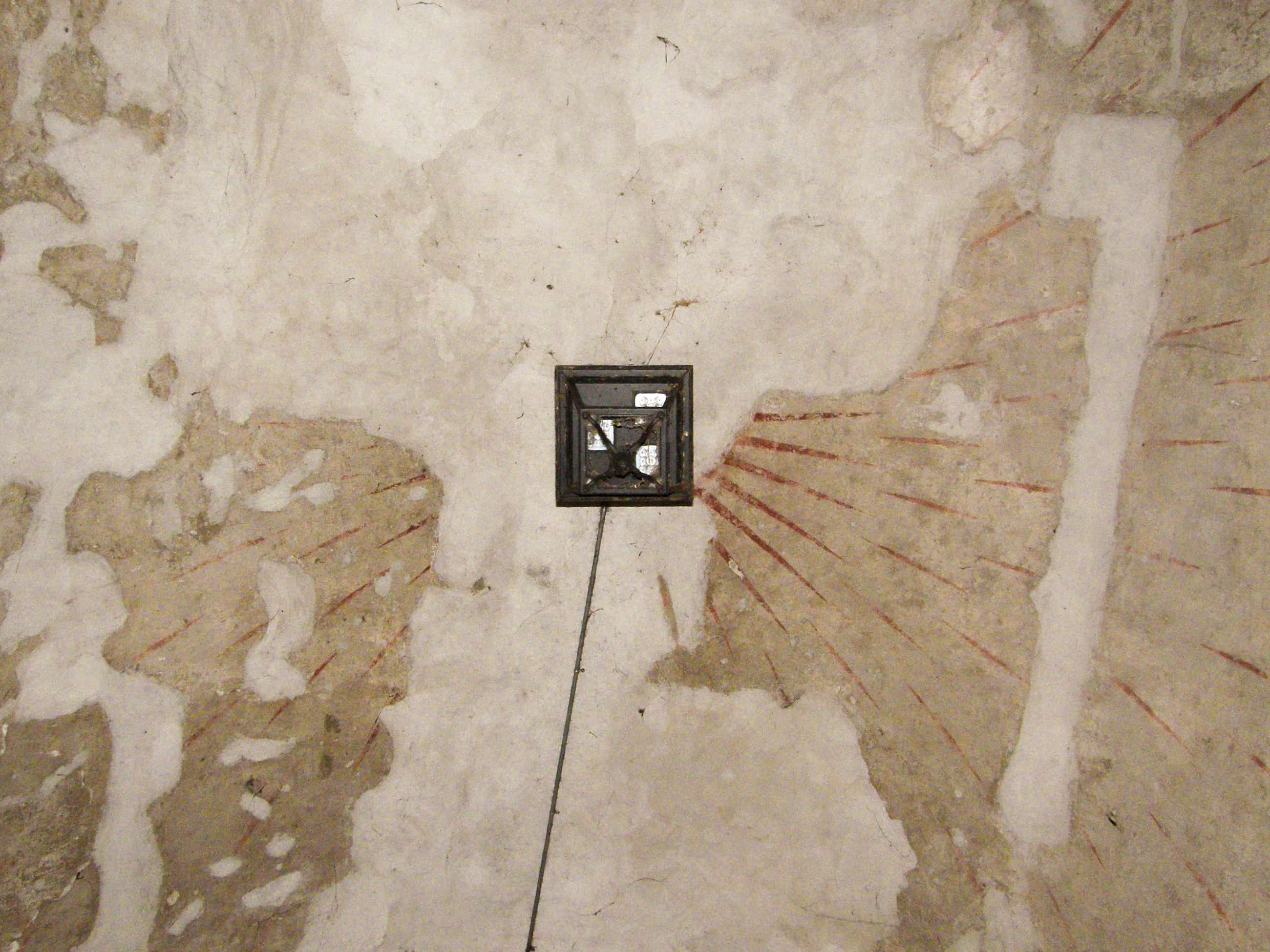 Un paese nuovo, Ceresara, Libro. Parete antica con pittura sbiadita che mostra raggi rossi emergenti da una piccola finestra quadrata nera al centro.