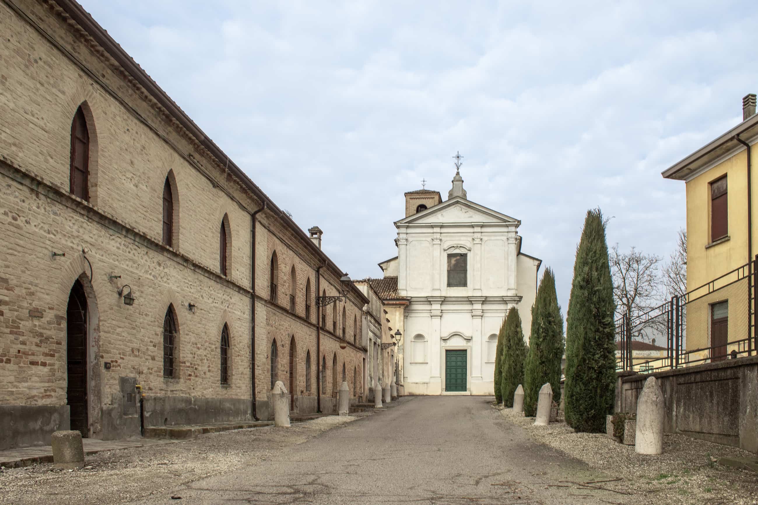 Un paese nuovo, Ceresara, Libro. Facciata di una chiesa bianca in fondo a una strada con cipressi e edifici storici ai lati.