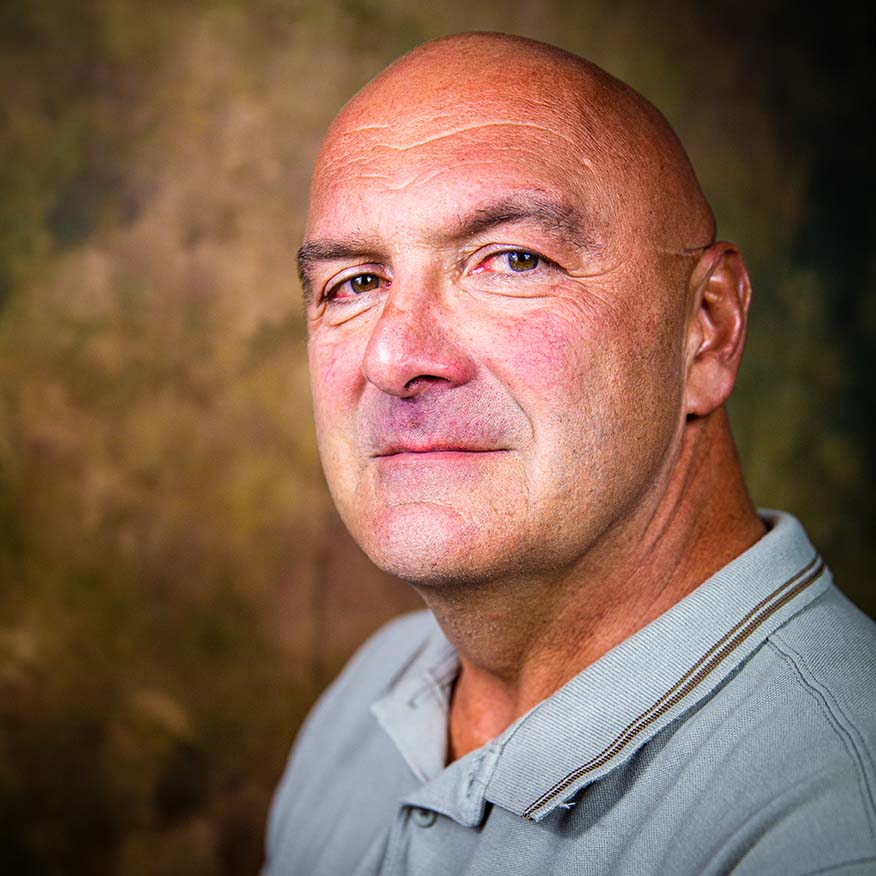 I segni del mestiere, Campagna sociale. Primo piano di uomo calvo con camicia grigia che guarda verso la fotocamera con espressione neutra.