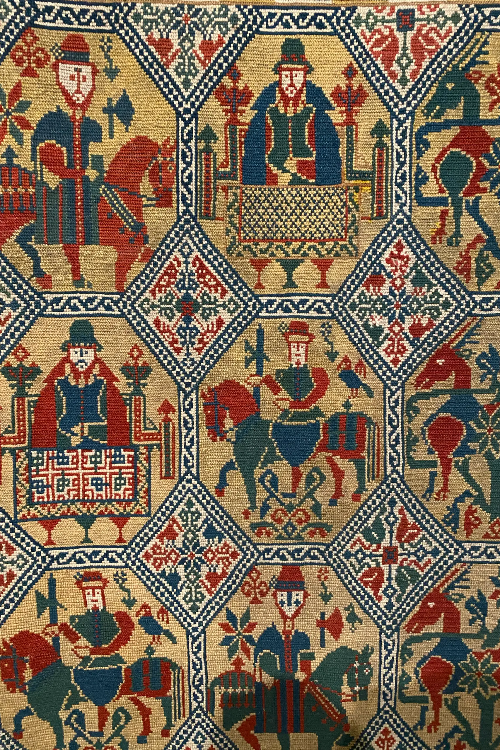 Islanda in auto, libro, Daniel Cortese. Tessuto intrecciato con motivi tradizionali raffiguranti cavalieri con cappelli e strumenti, insetti e fiori in colori rosso, blu e beige.