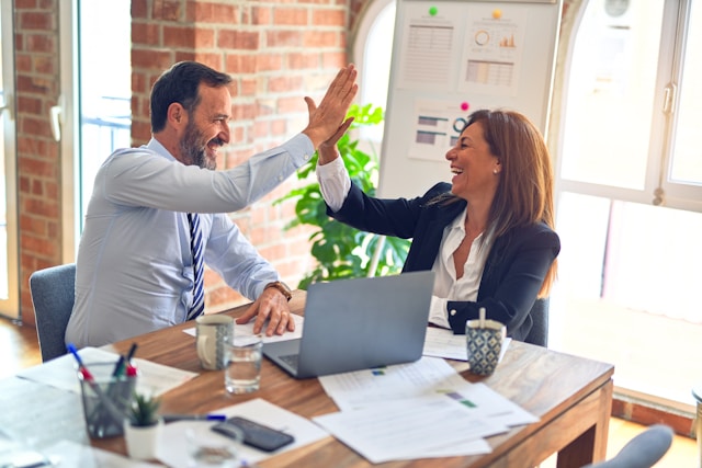Two people working together, giving each other a high five.