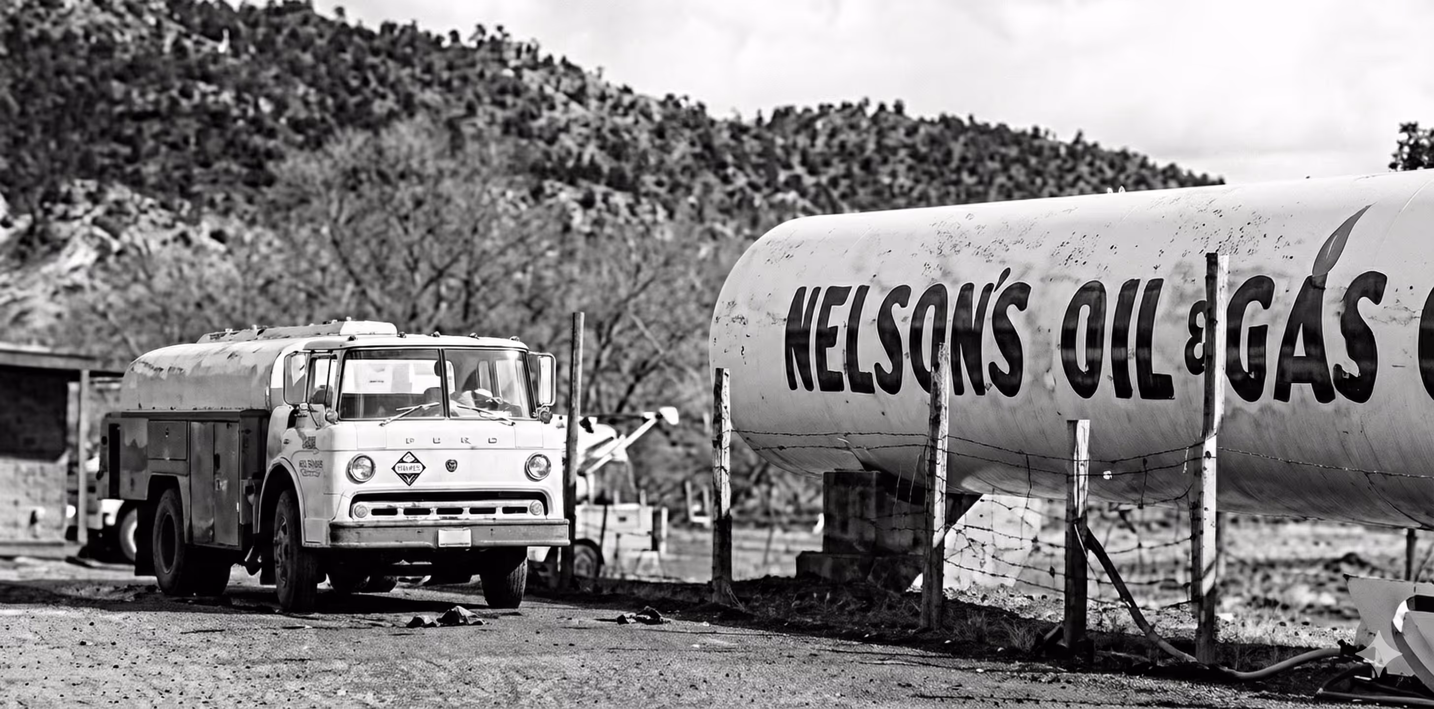 Black-and-white photo of a vintage Ford fuel truck parked next to a large Nelson's Oil & Gas storage tank in a rural setting.