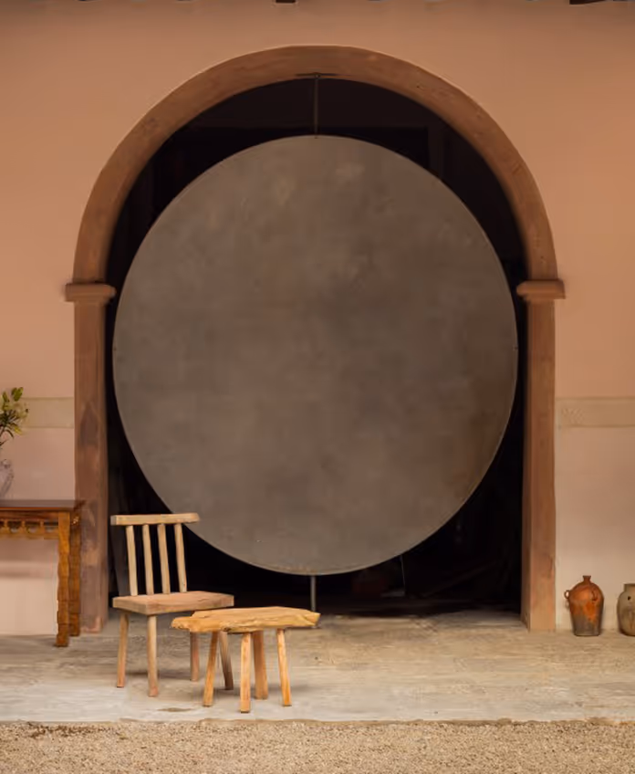 Architectural detail at La Valise Tulum featuring a large circular metal door and handcrafted wooden furniture.