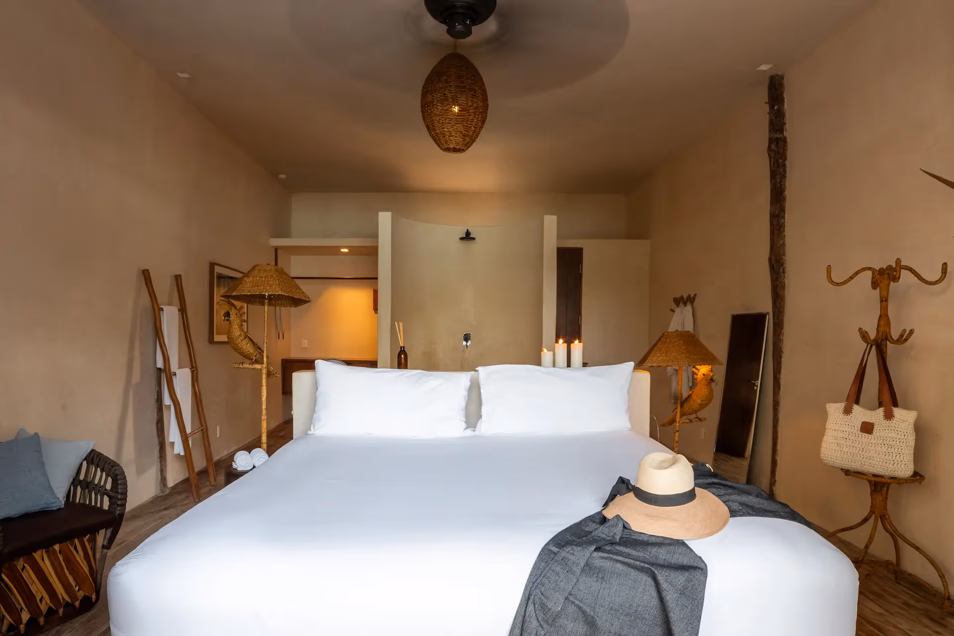 Luxury bedroom interior at La Valise Tulum hotel featuring a large wooden bed, boho-chic decor, and a ceiling fan.