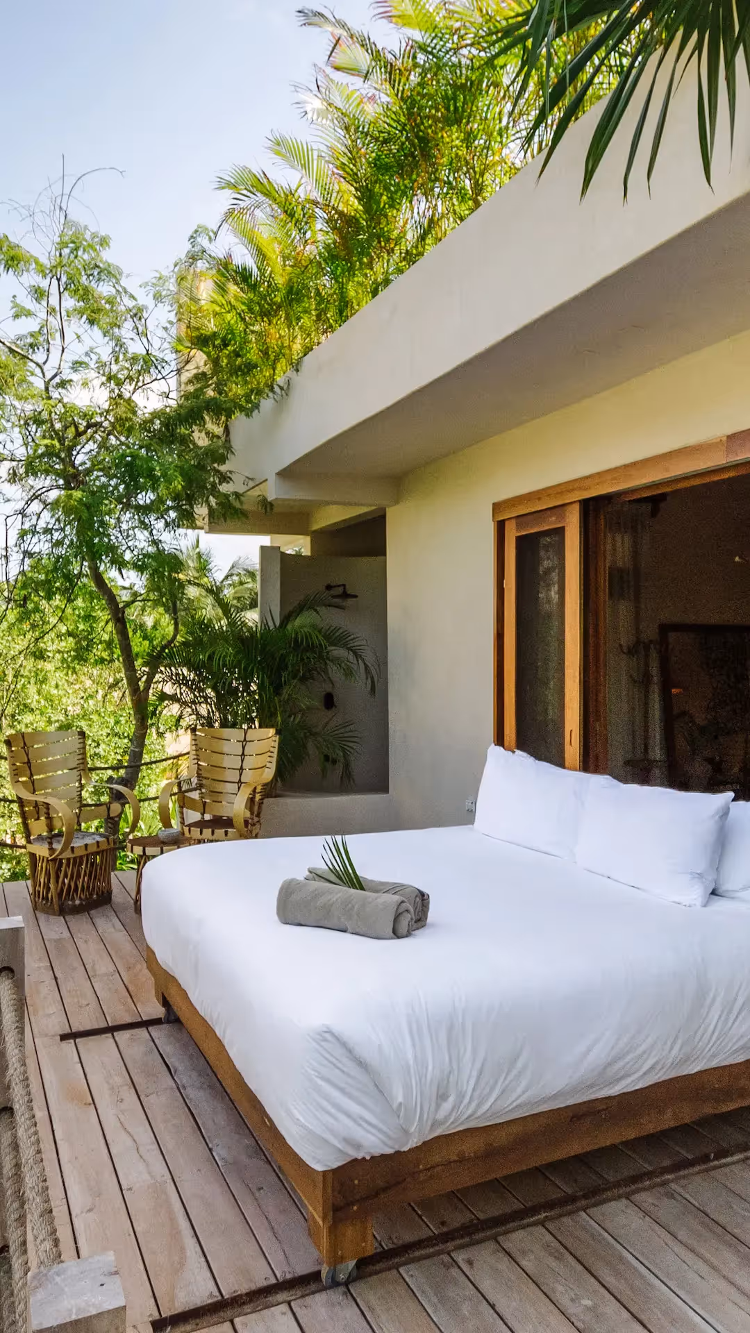 Outdoor bed on a wooden deck at La Valise Tulum hotel, surrounded by tropical jungle greenery.