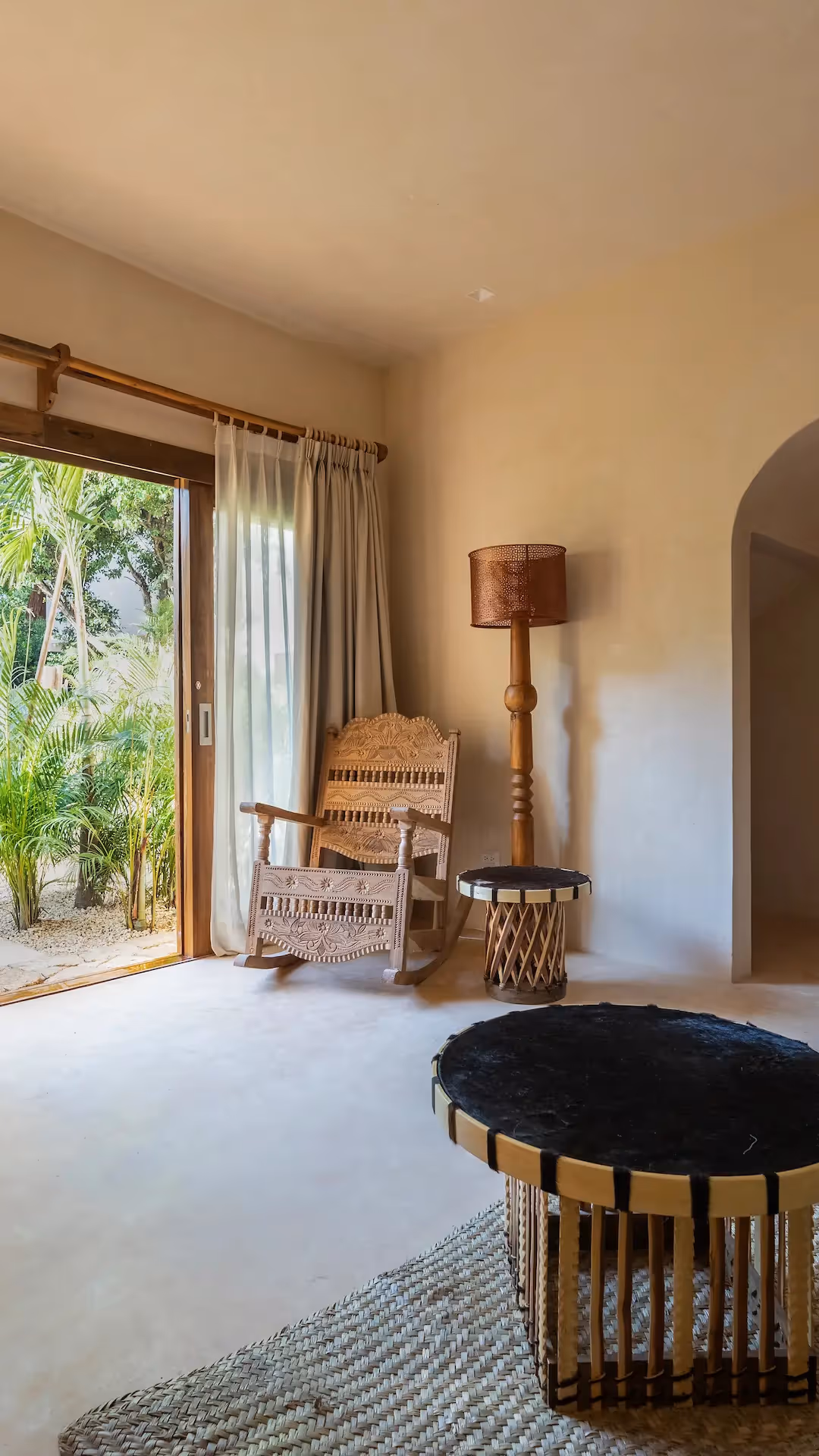 Elegant living area at La Valise Tulum featuring artisanal furniture and a large opening to a lush tropical terrace.