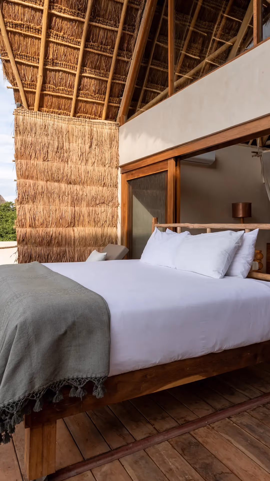 Panoramic terrace at La Valise Tulum featuring an outdoor bed and traditional wooden architecture.