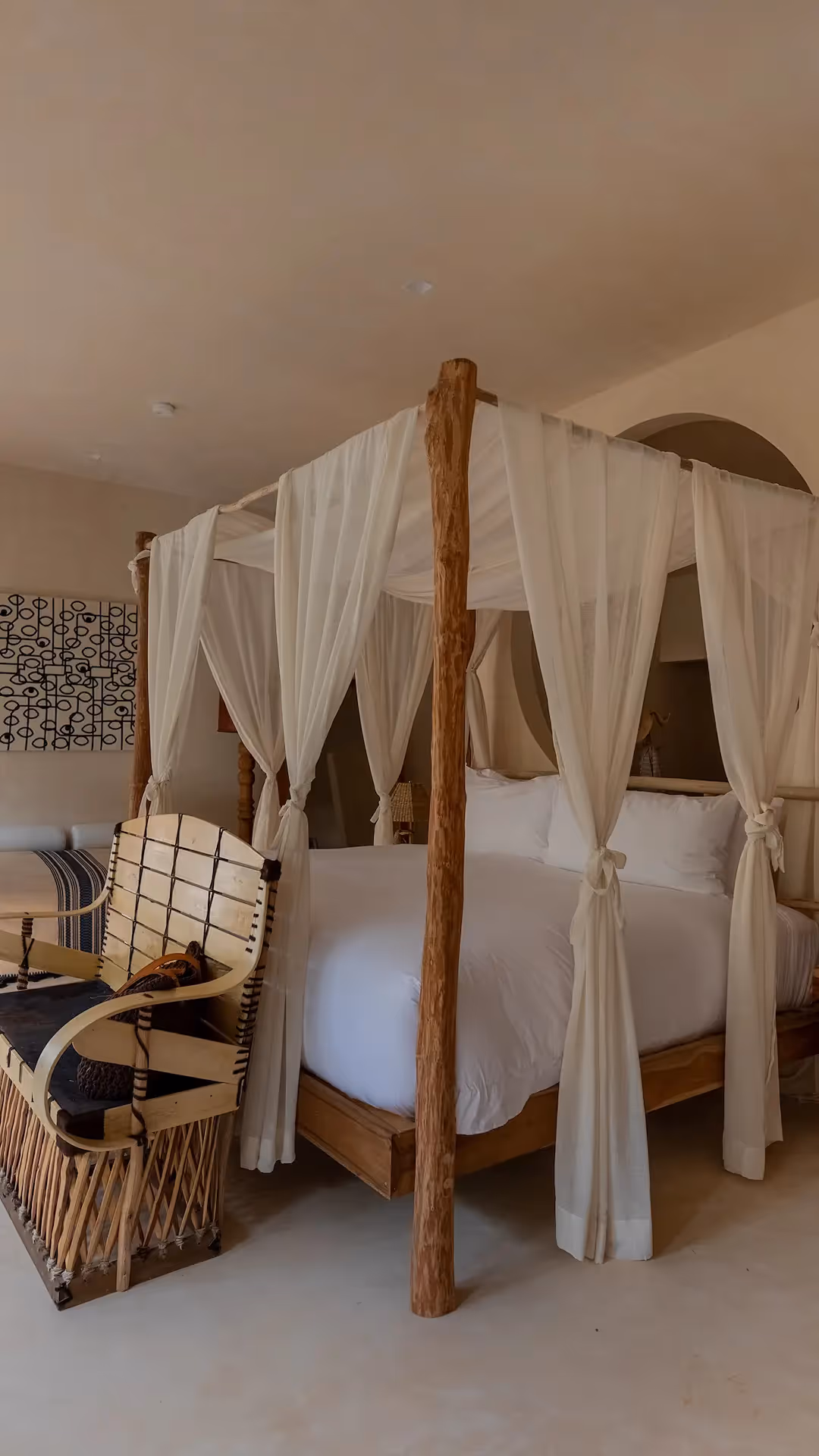 Luxury guest room featuring a four-poster canopy bed with white linens at La Valise Tulum hotel, Mexico.