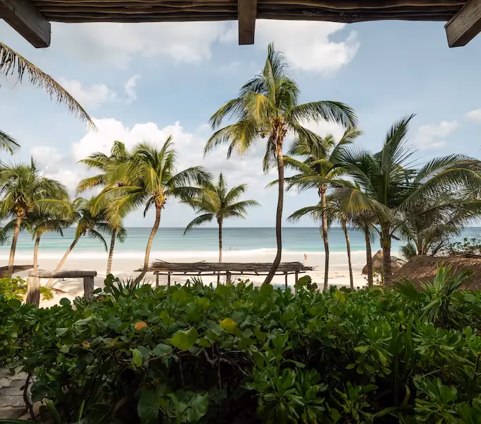 Vista desde arriba de una mujer con sombrero para el sol caminando junto a una piscina turquesa en el hotel La Valise Tulum.