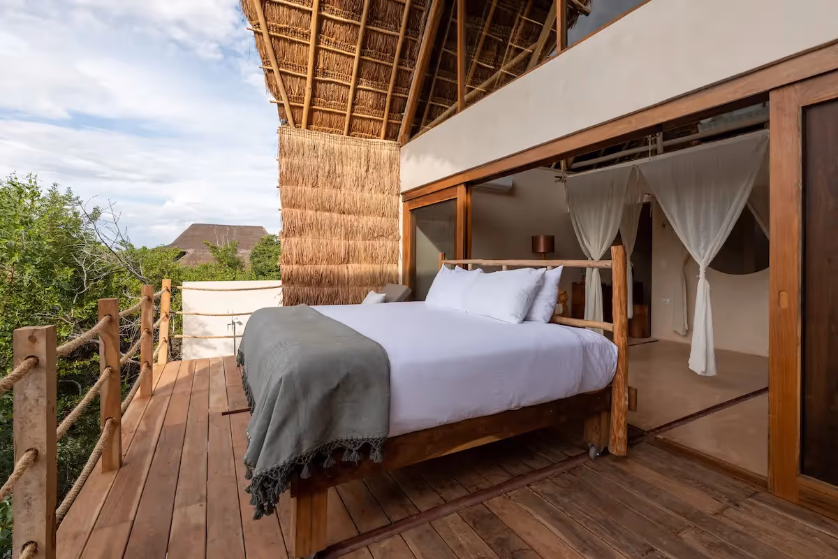 Luxury suite with an outdoor bed on a wooden terrace offering panoramic views at La Valise Tulum Hotel.