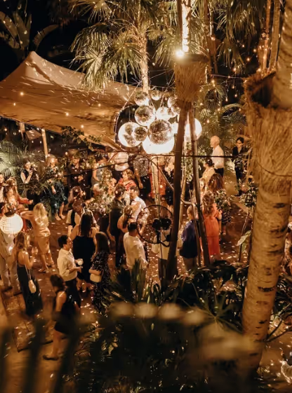 Recepción de boda nocturna con bolas de discoteca bajo las palmeras en La Valise Tulum.
